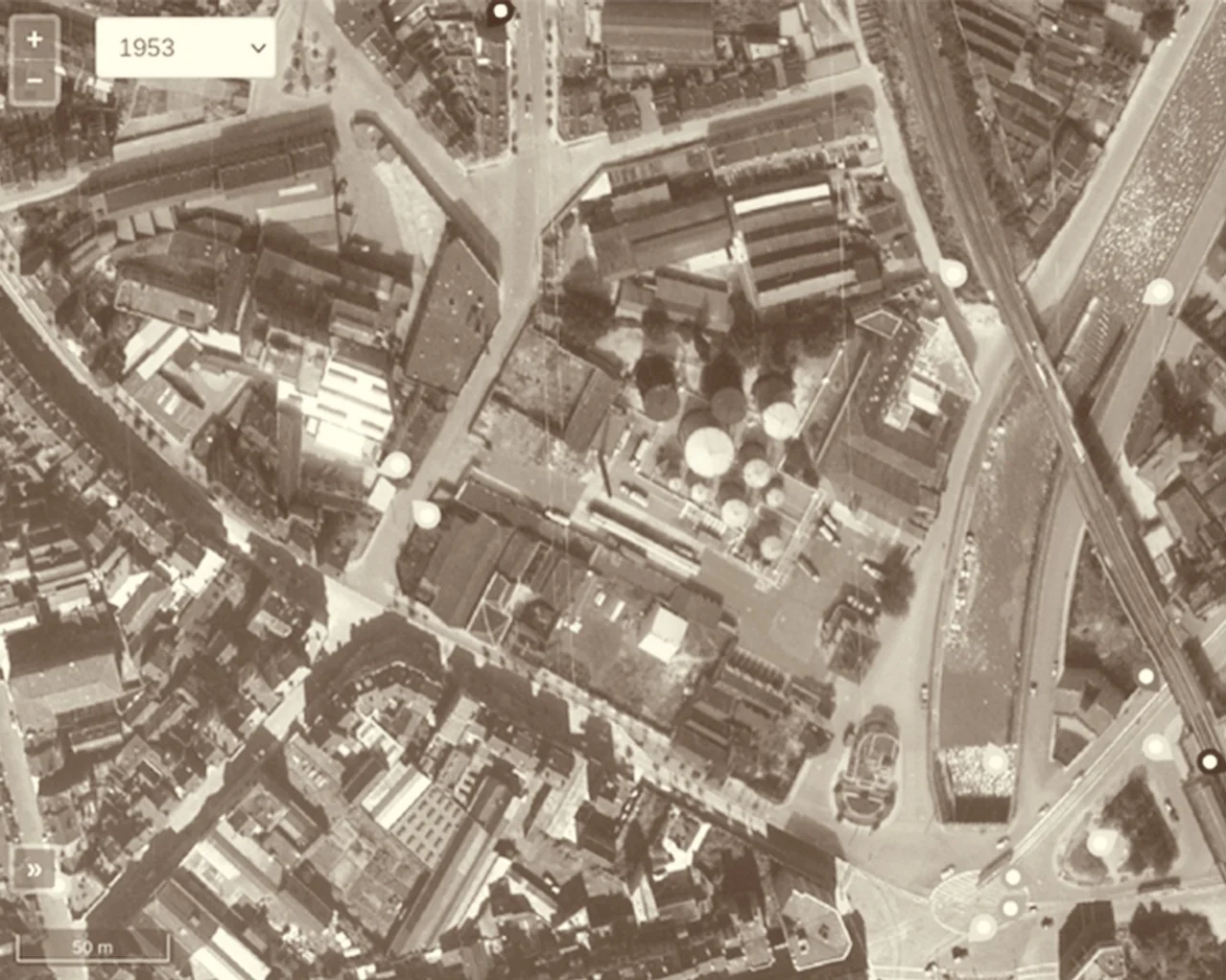 Vue aérienne de 1953 : les cuves rondes de Shell sont apparues au cœur de l’îlot, entre le canal et les rues du quartier