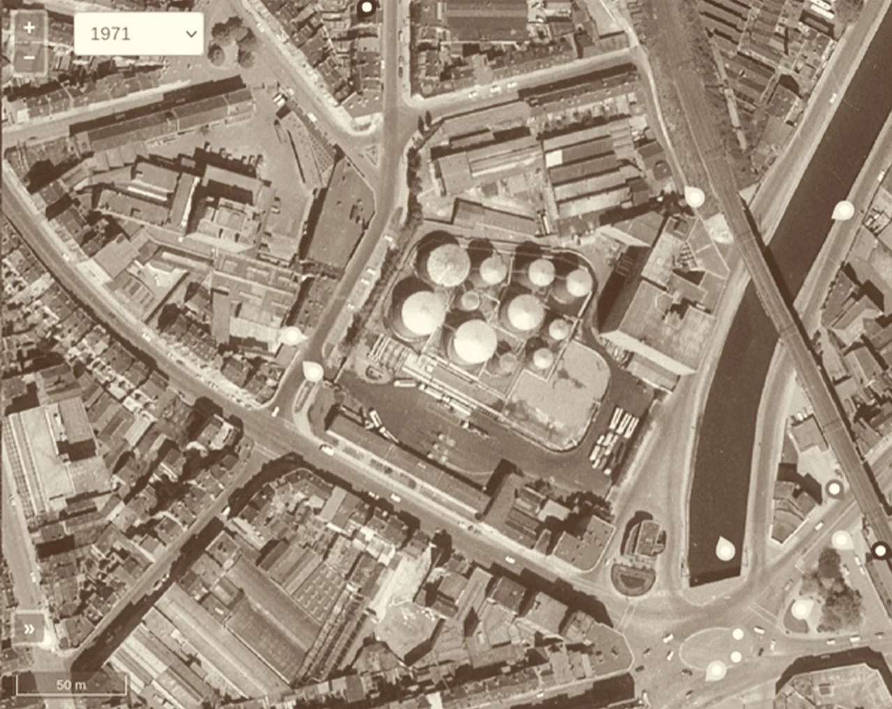 Vue aérienne de l’îlot Shell en 1971 : les cuves de stockage d’hydrocarbures occupent le centre de la parcelle, le canal longe le site à droite